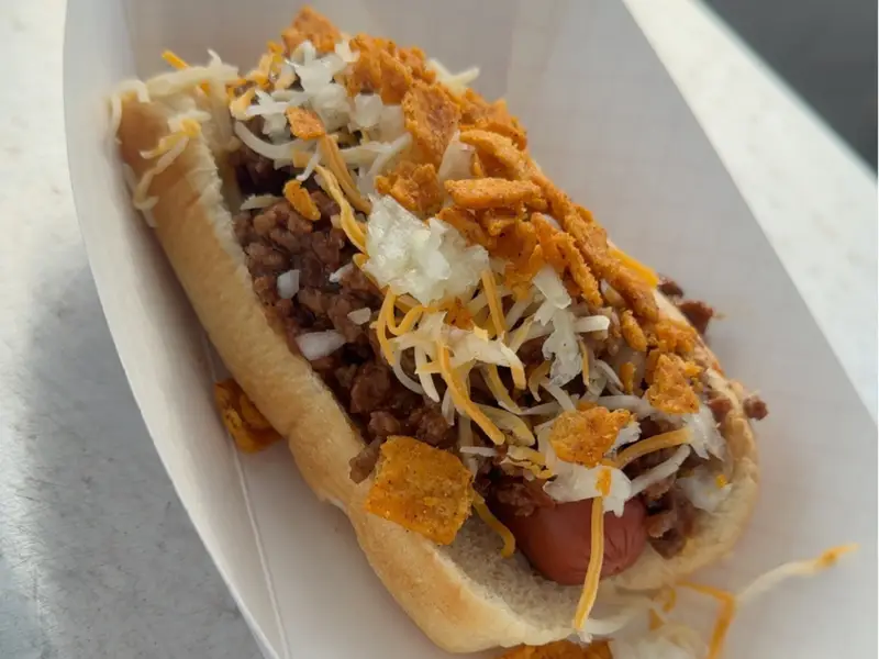 Chili dog topped with crushed Fritos, cheese, and onion from Diner's Choice Eats