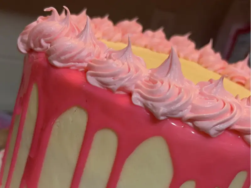 White iced cake with dripping pink icing by Diner's Choice Eats